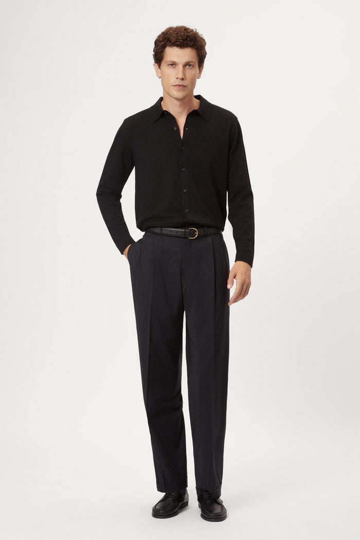 Man wearing a black shirt and grey pants on a white background