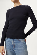 Woman wearing a blue sweater and light blue jeans on a white background