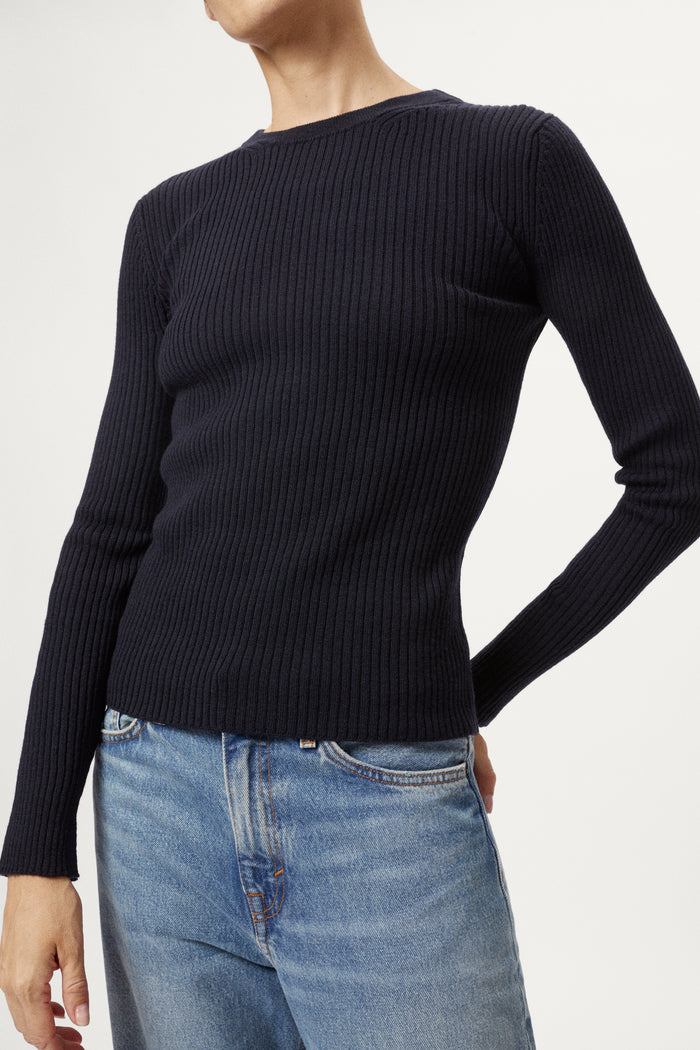 Woman wearing a blue sweater and light blue jeans on a white background