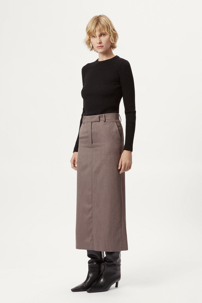 Woman wearing a black top and brown skirt on a white background