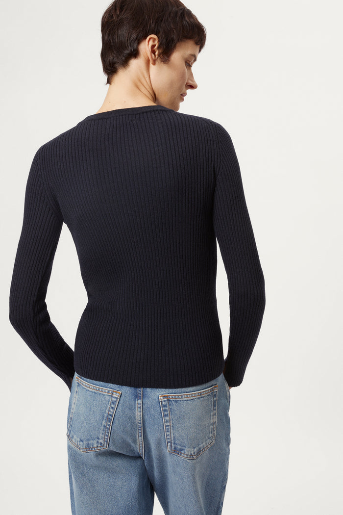 Woman wearing a blue sweater and light blue jeans on a white background