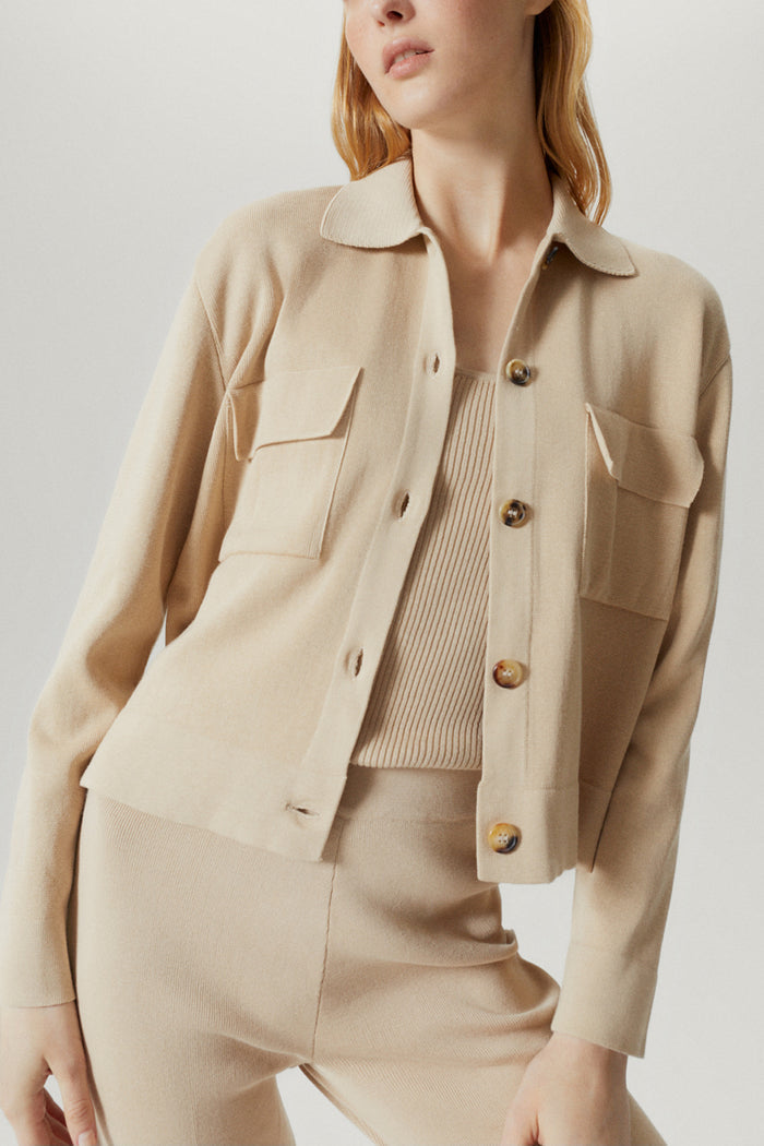Person wearing a beige jacket and pants on a plain background
