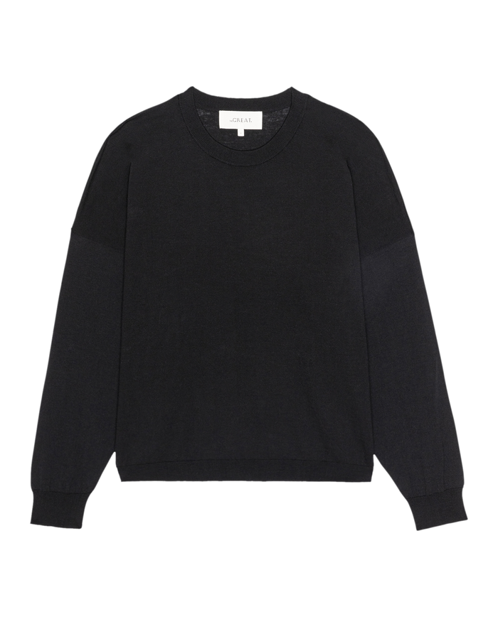 The Oversized Pullover by THE GREAT. SP26 D1 is a plain black, oversized long-sleeve crewneck sweater with ribbed cuffs and hem, shown on a white background.