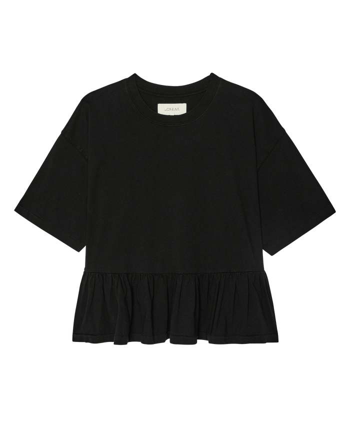 The Oversized Ruffle Peplum Tee in True Black by THE GREAT. SP26 DANCER BODIES features short sleeves, a round neckline, a peplum hem, and heavyweight jersey fabric, shown on a plain white background.