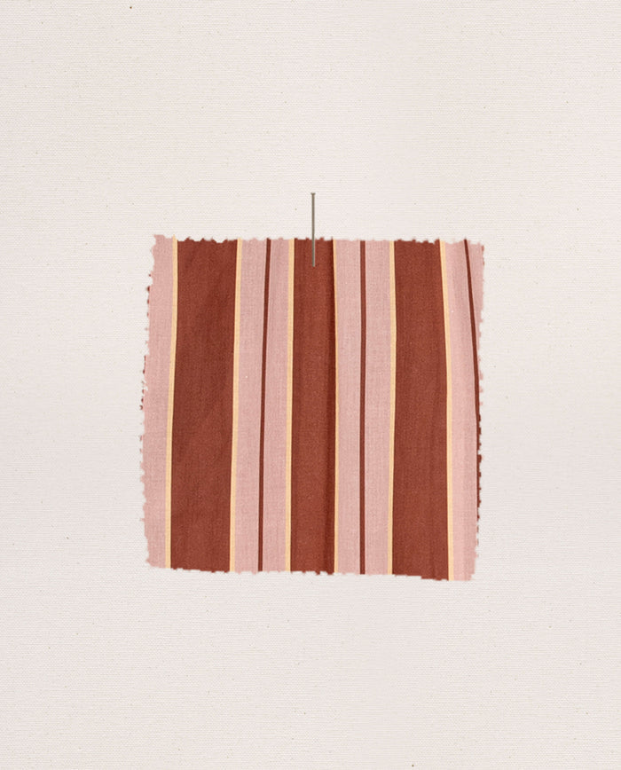 A rectangular swatch of THE GREAT. F26 SLEEP’s The Pajama Shirt -- Ganache Stripe fabric, featuring vertical stripes in shades of pink, brown, and beige inspired by classic pajama shirt patterns, pinned to a plain off-white background.