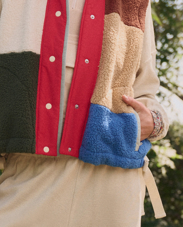 A person wearing THE GREAT. SP26 TGO Plush Color Block Sierra Vest in Canyon Multi over a light beige outfit, standing outdoors.
