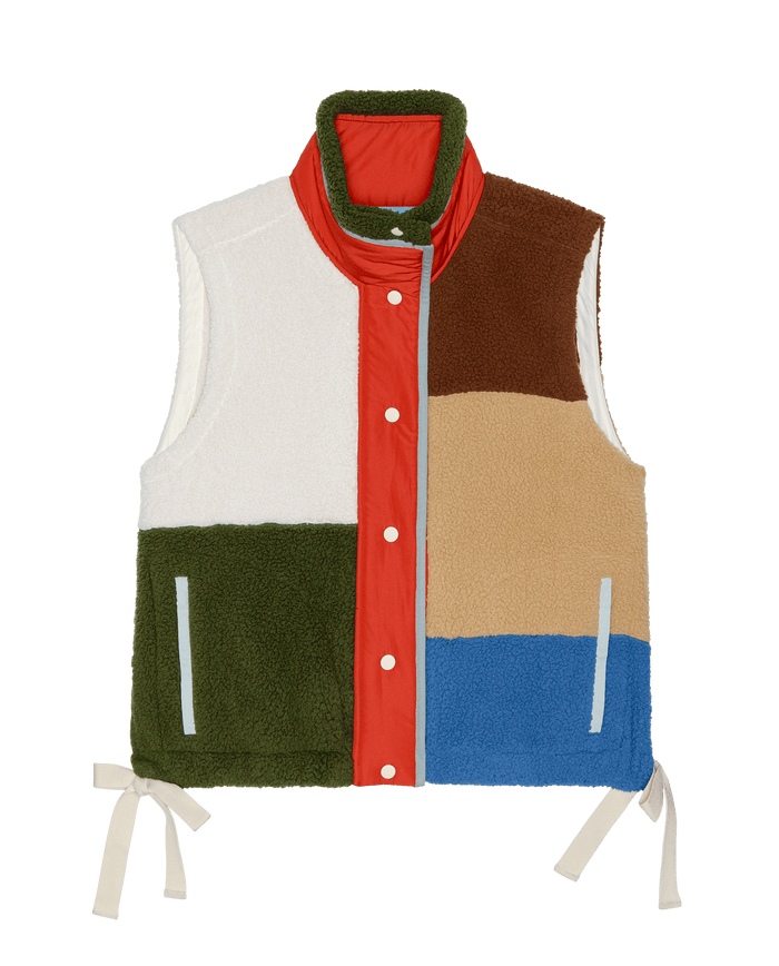The Plush Color Block Sierra Vest by THE GREAT. in Canyon Multi is a sleeveless, collared vest with snap buttons, bold color panels in white, brown, tan, green, blue, and red, plus side ties and two front pockets for style and function.