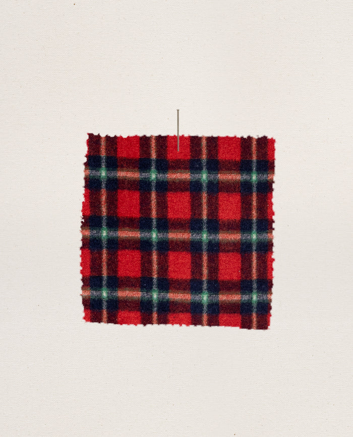 A rectangular swatch of Cedarwoods Plaid fleece fabric, from THE GREAT. H25 SLEEP's Plush Fleece Pajama Pant, is displayed pinned to a plain white background.
