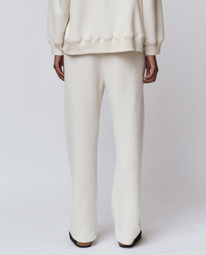 Model wears THE GREAT. H25 TEDDY FLEECE's The Plush Victory Sweatpant in Washed White, handcrafted in L.A. from ultra-soft fleece, photographed from the back against a plain white background.