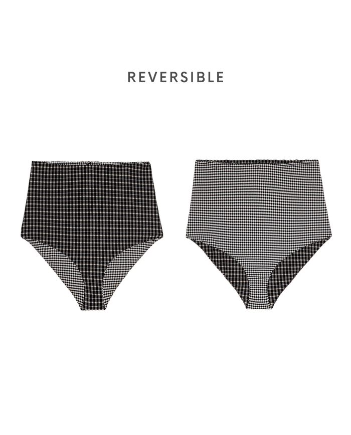 THE GREAT. SP26 SWIM's Reversible High Rise Covered Brief in Black & Cream Check is shown with both black and cream checkered patterns, highlighting a vintage 50s-inspired style against a plain background.