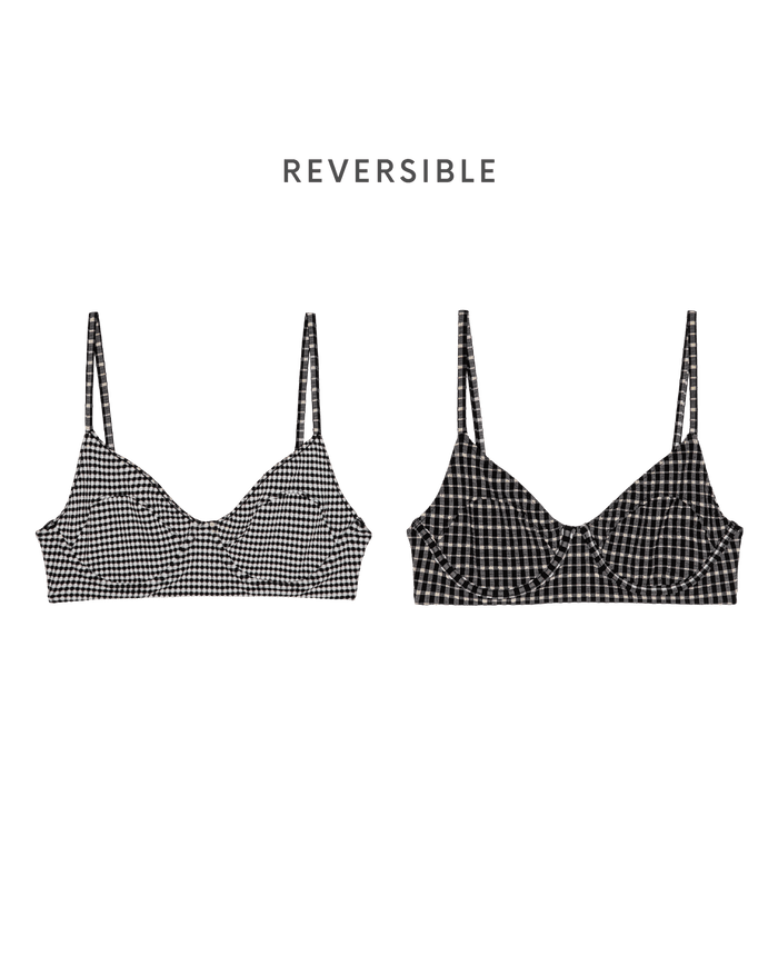 Two front-facing "The Reversible Underwire Bikini Top" by THE GREAT. SP26 SWIM in Black & Cream Check—one in a light, the other in a dark checkered pattern—channeling 1940s bikini style, with "REVERSIBLE" text above.