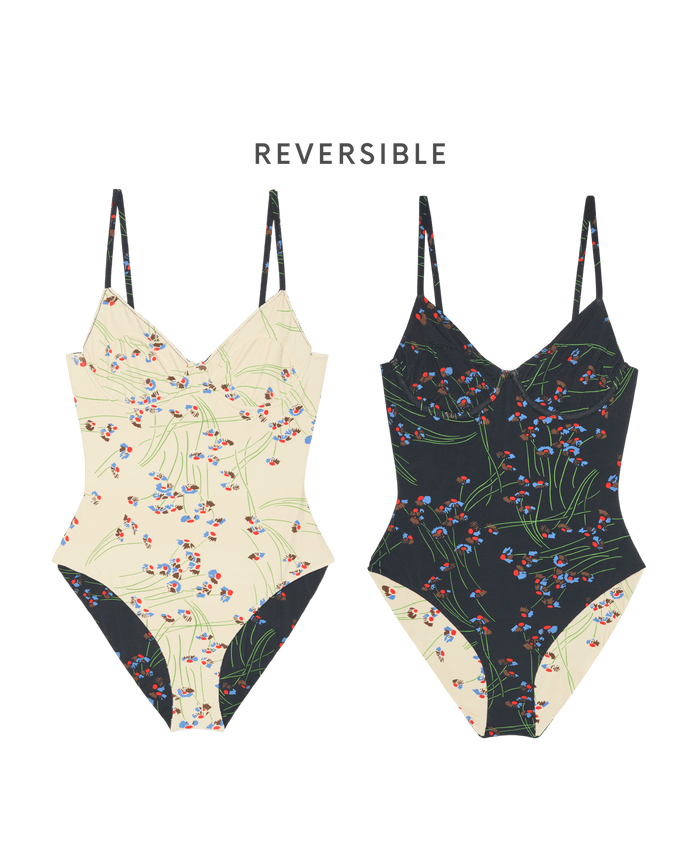 Two front-facing "The Reversible Underwire One Piece - Windblown Bouquet" swimsuits by THE GREAT. SP26 SWIM: each shows a light floral on one side and a dark, vintage-inspired floral on the other. "Reversible" appears above them.