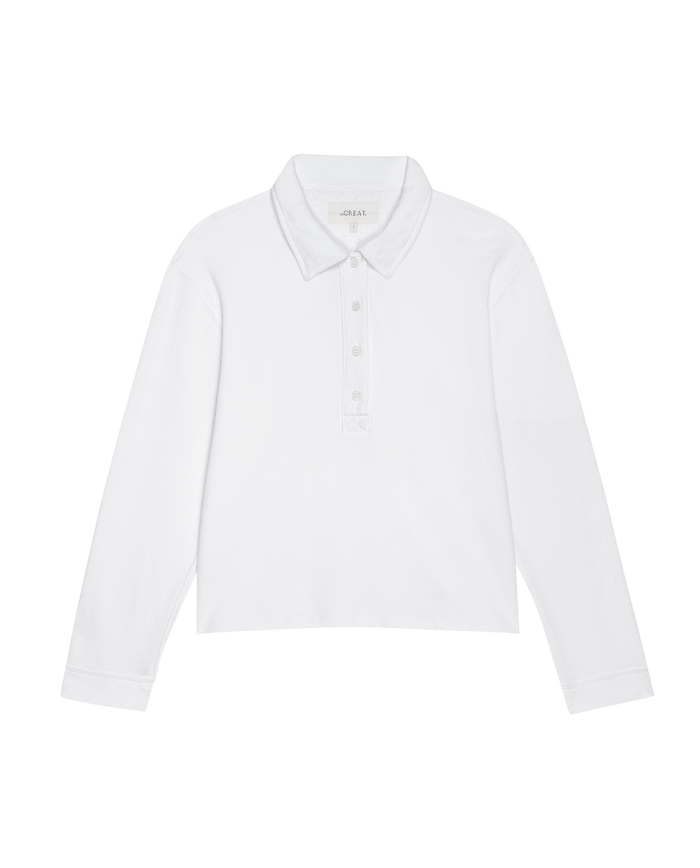 The Rugby Sweatshirt by THE GREAT. SP25 POLO LOUNGE in True White features a collar, button placket, and long sleeves. Ideal for casual wear, it is set against a plain black background.