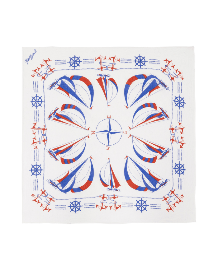 The Sailboat Bandana by THE GREAT. SU26 features a white vintage look with blue and red sailboats, compasses, anchors, and ship wheels in a symmetrical nautical pattern.