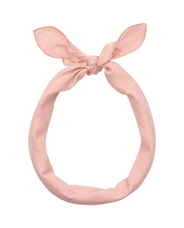 The Scalloped Bandana in Petal by THE GREAT. SU26 is a light pink headband with a top knot, bunny ear-like pointed ends, and subtle scalloped edges, shown on a plain white background.