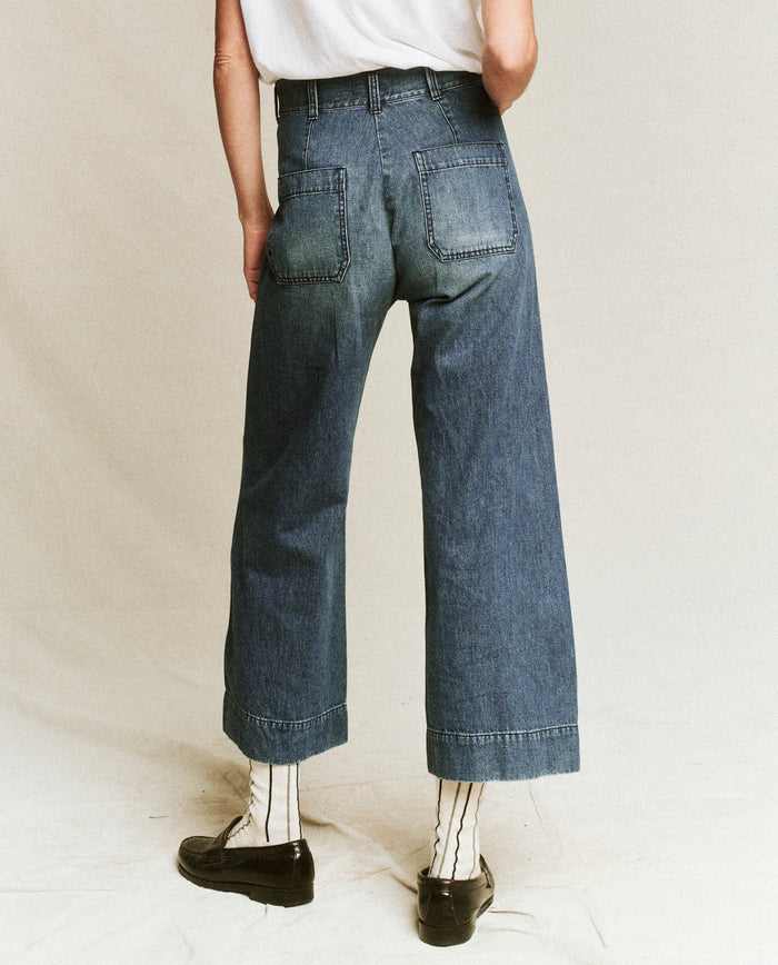 Person wearing The Seafair Jean -- Marina Wash by THE GREAT. PF24, a white t-shirt, striped socks, and black shoes, standing with their back facing the camera.