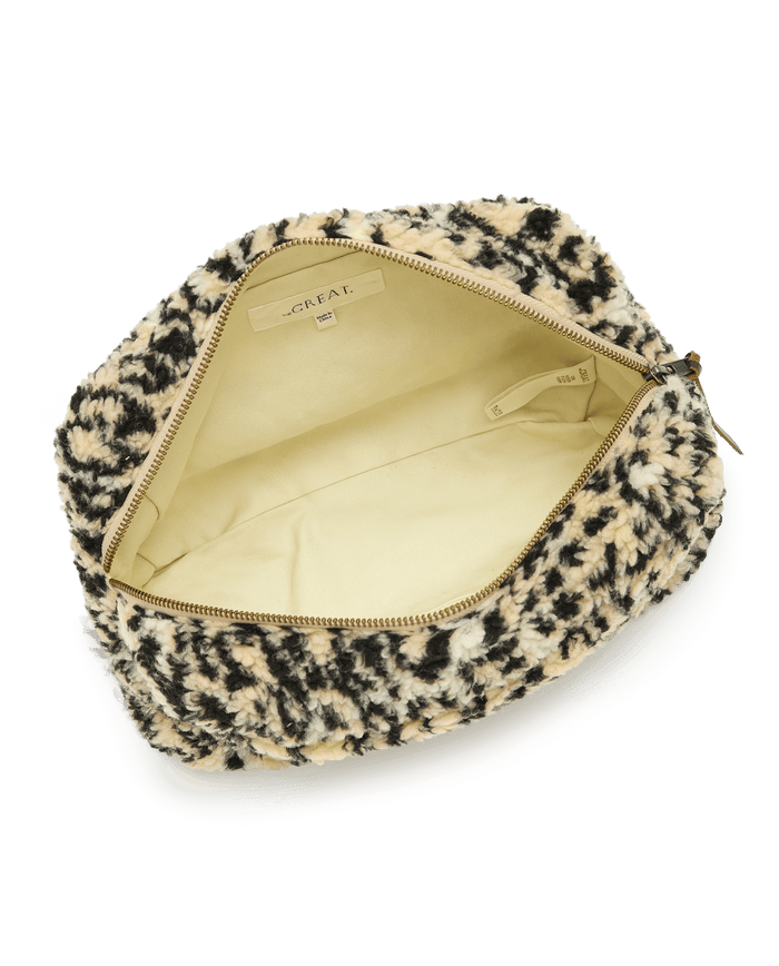 Discover "The Sherpa Pouch - Leopard" by THE GREAT. HOL 24 ACCESSORIES, boasting a chic leopard-print fuzzy exterior and a warm beige interior, complete with an easily accessible zipper.