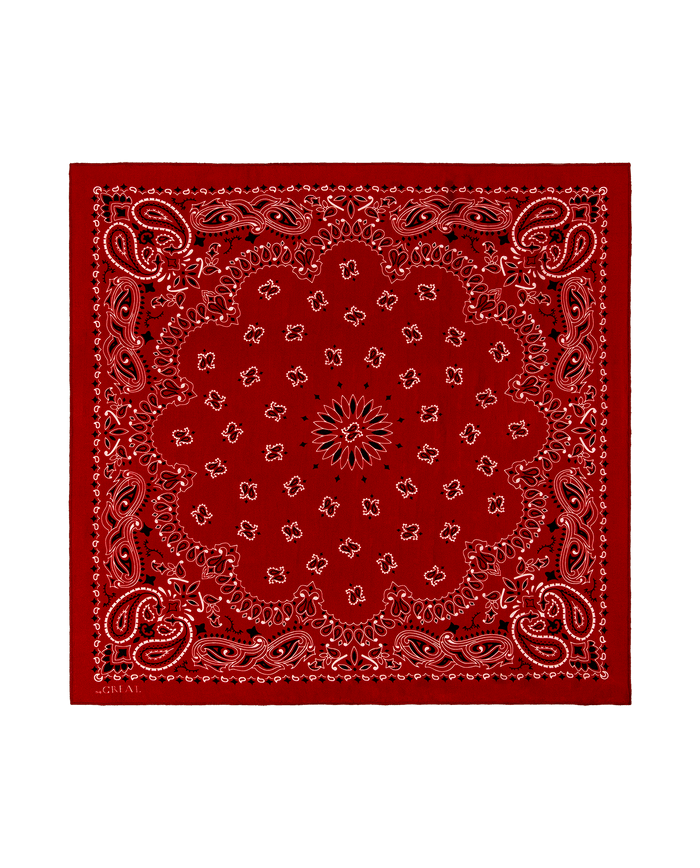 The Silk Bandana by THE GREAT. F25 COLLECTORS in True Red features a white and black paisley and floral border on luxurious, lightweight silk, capturing the vintage charm of classic bandanas. Displayed on a white background.