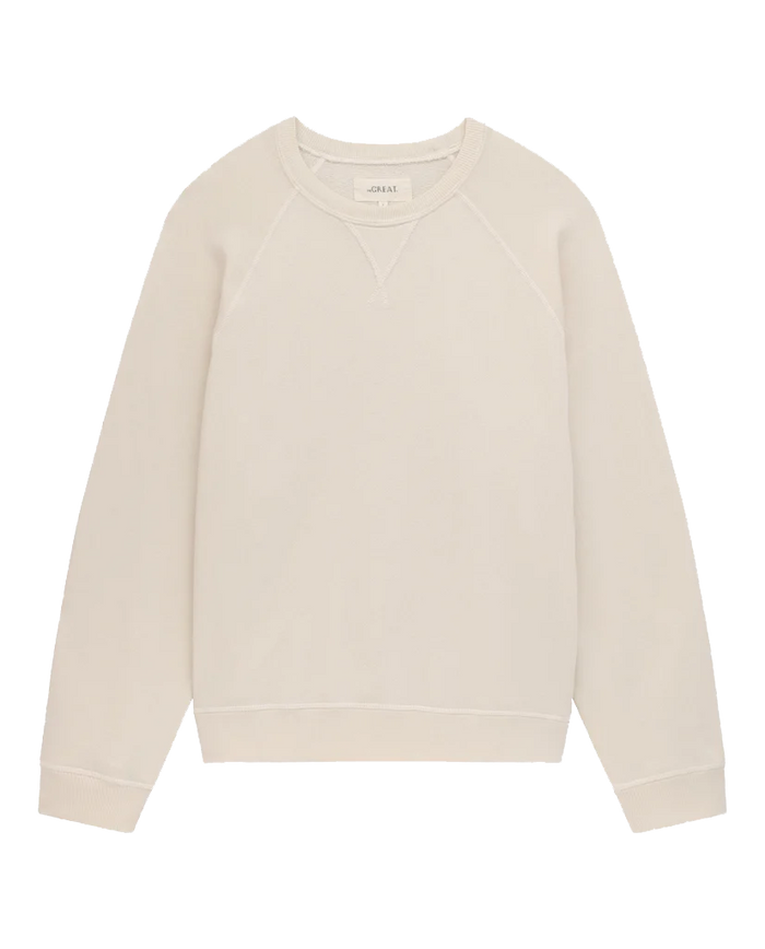 A plain, washed white crewneck vintage sweatshirt with long sleeves and a stitched V-neck detail at the collar, made in the USA from 100% cotton. This is The Slouch Sweatshirt by THE GREAT. CORE KNITS.