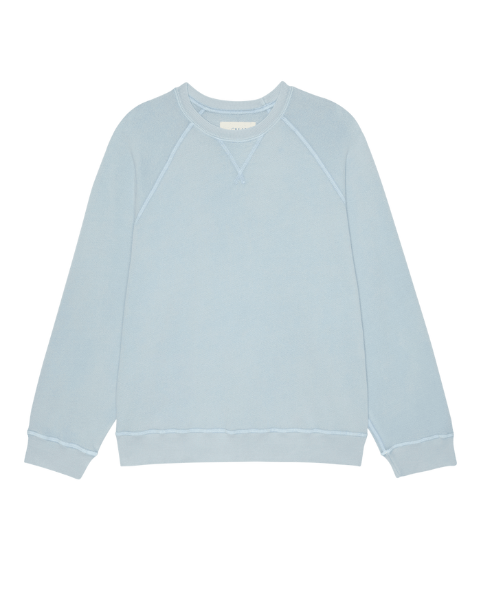 The Slouch Sweatshirt in Whisper Blue by THE GREAT. SP26 SEASONAL CORE features long sleeves, ribbed cuffs and hem, a small stitched neckline detail, and is handcrafted in Los Angeles; shown on a plain white background.