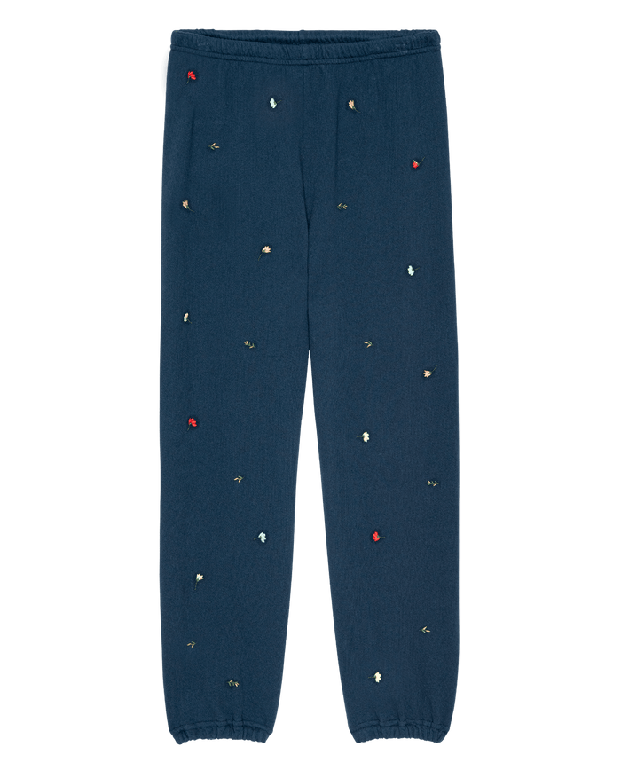 The Stadium Sweatpant W/ Tossed Floral Emb. in navy by THE GREAT. PS26 features an elastic waistband and cuffs with small multicolored embroidered florals—a vintage-inspired Los Angeles casual essential.