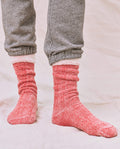 A person stands on a light fabric surface wearing gray sweatpants with a matching sweatshirt, paired with THE GREAT. SP25 SWEATSHIRT SOCKS in Red Cherry.