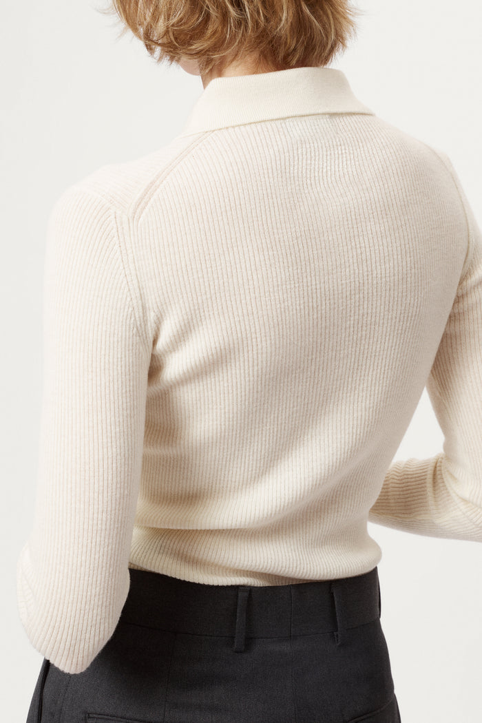 Woman wearing a white merino shirt and dark gray pants on a white background