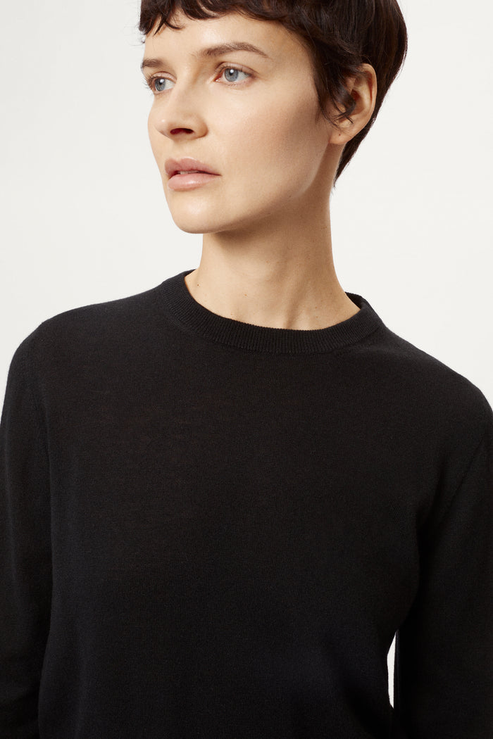 Person wearing a black sweater and black pants on a white background
