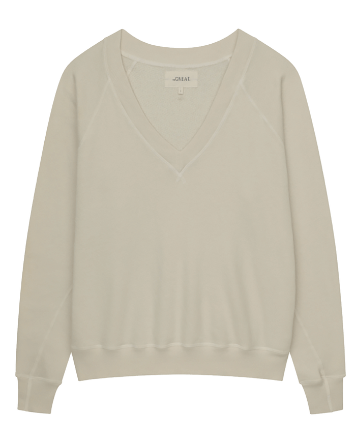 The V-Neck Sweatshirt in Washed White by THE GREAT. FALL 24 KNITS, featuring long sleeves, displayed against a white background.