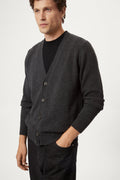 Man wearing a dark gray woolen cardigan over a black shirt on a white background