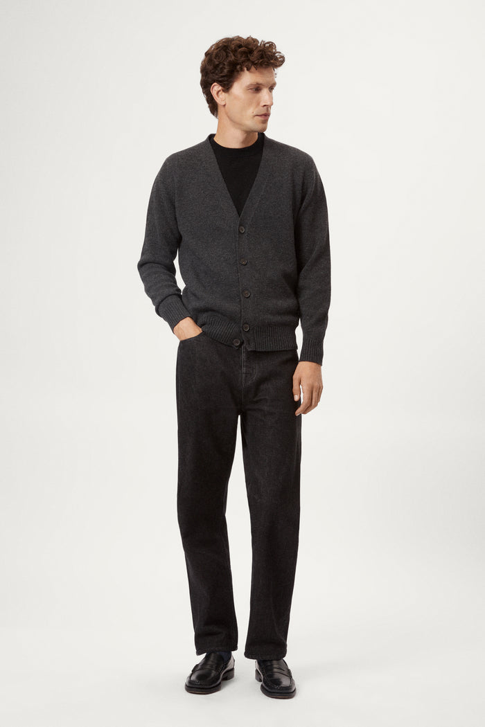 Man wearing a dark gray woolen cardigan over a black shirt on a white background