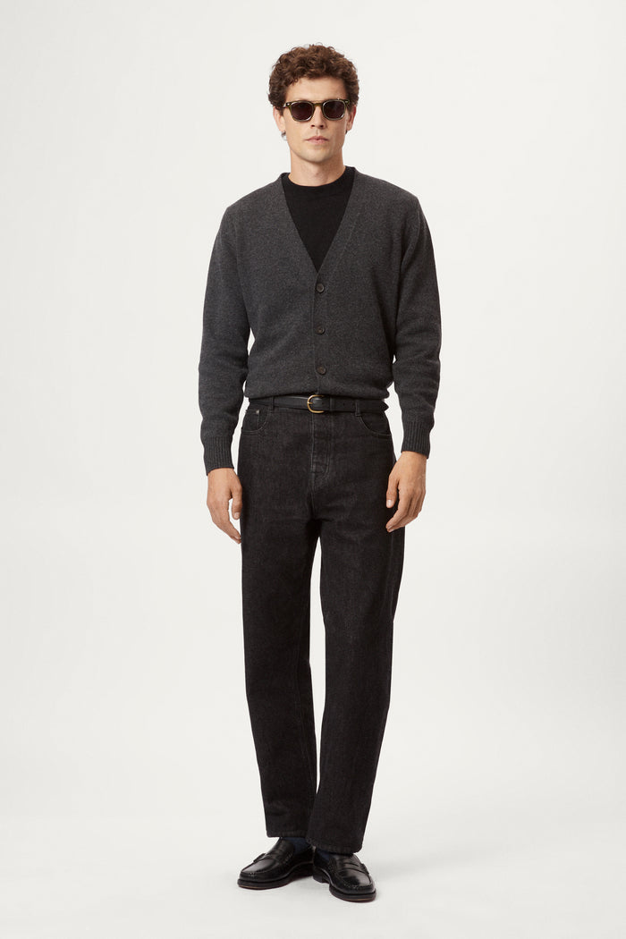 Man wearing a dark gray woolen cardigan over a black shirt on a white background