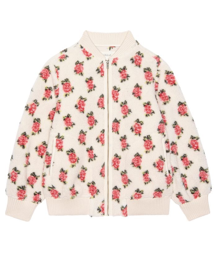 The Zip Front Plush Bomber in Cream Rose by THE GREAT. H25 ROSEBUD is a white zip-up jacket with an all-over pink and green floral pattern and ribbed cuffs, collar, and hem, inspired by a vintage hiking jacket.